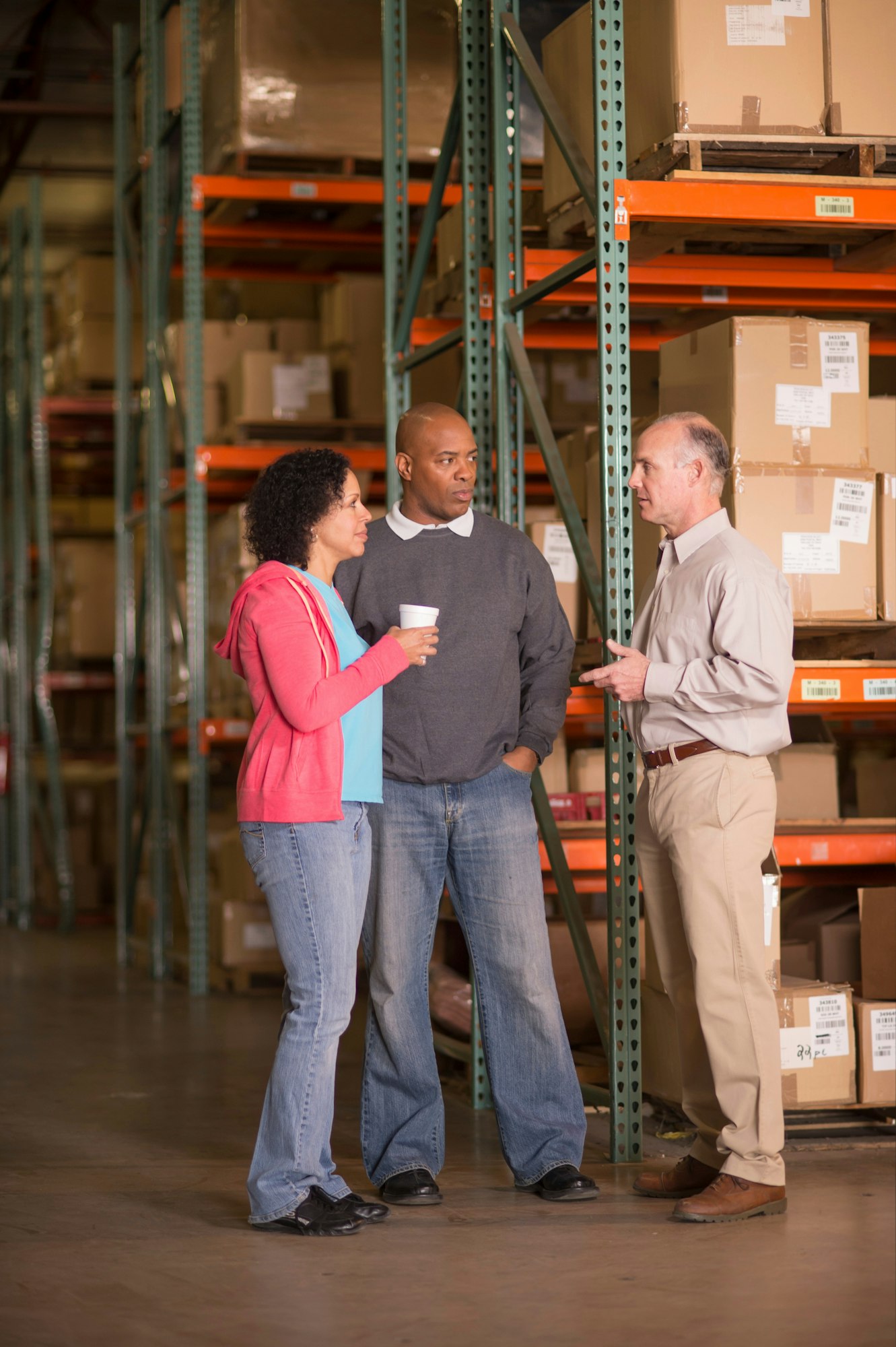 Warehouse workers standing by shelves with boxes